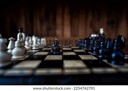 Blurred background with a low depth of focus. The set of wooden chess pieces elements standing on chess board on dark background. Leadership, teamwork, partnership, business strategy concept.