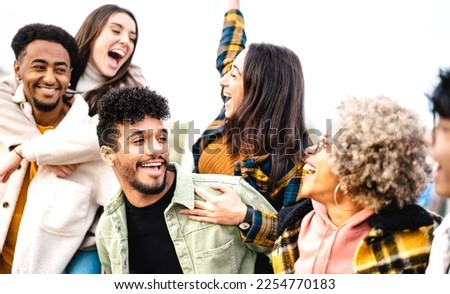 Milenial people cheering together open air on trendy life style concept - Happy guys and girls having fun outside acting piggyback move - University students on travel vacation  - Bright vivid filter Royalty-Free Stock Photo #2254770183