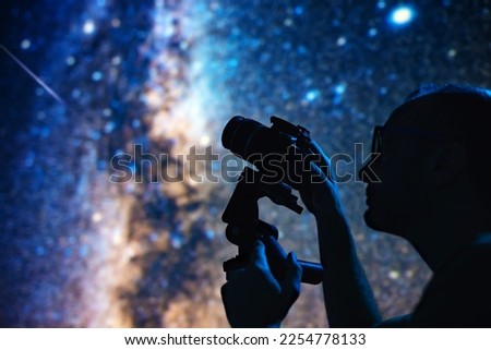 Astronomer photographing Milky Way night sky with a camera.