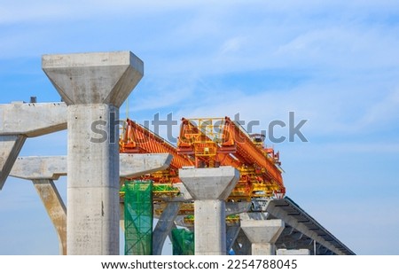 Metal launching gantry Structure for installing concrete typical Segment Joint on foundation of Elevated Expressway in road Construction site against clouds on blue sky background Royalty-Free Stock Photo #2254788045