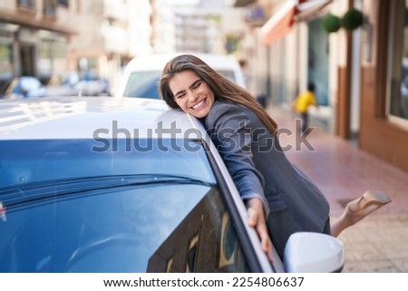 Young woman smiling confident hugging car at street