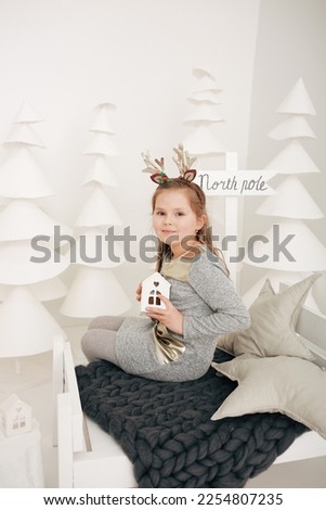 a girl in a gray dress and a New Year photo zone. paper white Christmas trees. children's Christmas photo zone, in the style of the North Pole