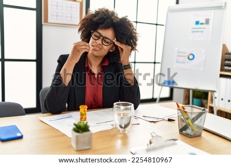 Young african american woman taking pill at office