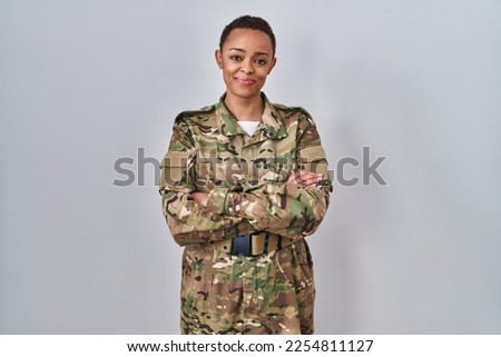 Beautiful african american woman wearing camouflage army uniform happy face smiling with crossed arms looking at the camera. positive person. 