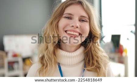 Young blonde woman preschool teacher smiling confident standing at kindergarten