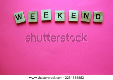 WEEKEND - a word on wooden cubes on a pink background. Information concept. View from above. End of the working week. Rest. Word on top