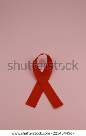 Photograph of red ribbon on pink background.