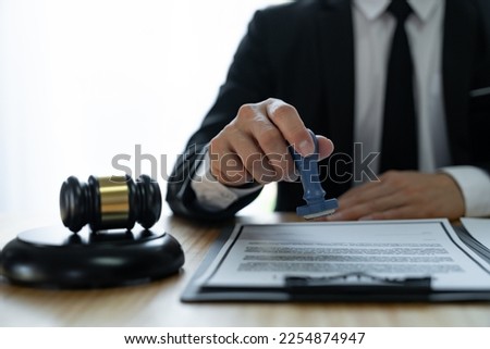 Young Asian legal advisor or lawyer doing document approval stamp Business agreements regarding real estate financial documents at the office. Royalty-Free Stock Photo #2254874947