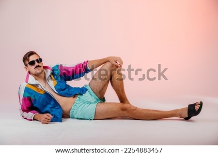 Back in time 90s 80s lifestyle concept. Studio footage of stylish cheerful young man in vintage retro jacket on light pink background, candy-colored fashions, creativity, emotions, facial expression Royalty-Free Stock Photo #2254883457
