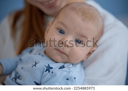 Loving mother takes care of a newborn baby at home. Bright portrait of a happy mother holding a baby in her arms. Mother hugging her little two month old son. Happy family concept.