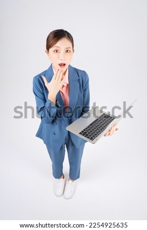 Full length photo of young Asian businesswoman using laptop