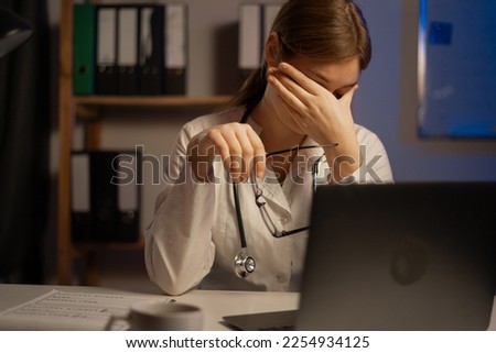 Tired doctor or nurse sitting at table during night shift. Copy space Royalty-Free Stock Photo #2254934125