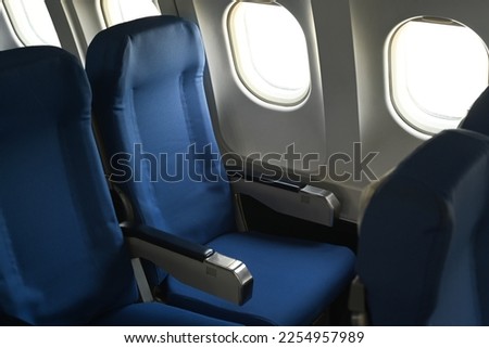 Airplane cabin interior, empty comfortable seats in economy class with portholes Royalty-Free Stock Photo #2254957989