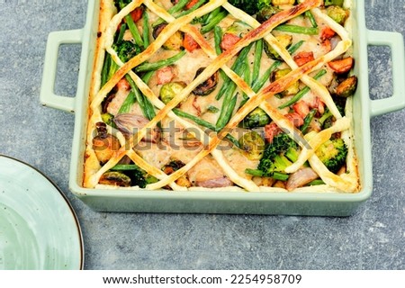 Meat pie with brussels sprouts, pumpkin and broccoli in baking dish. Autumn pie.