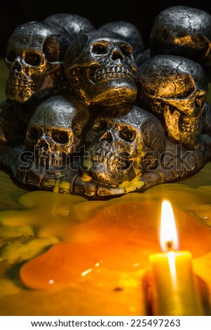 skulls with candle burning on wooden background in the darkness