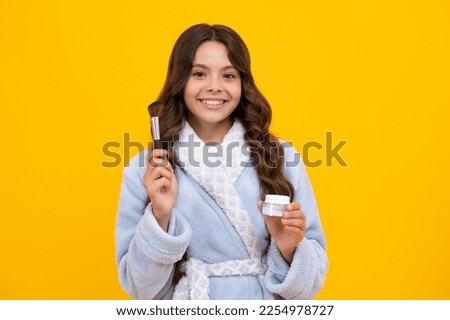 Beauty, make up and kids cosmetics. Teenage child girl with brush applying blush to face isolated on wellow background.