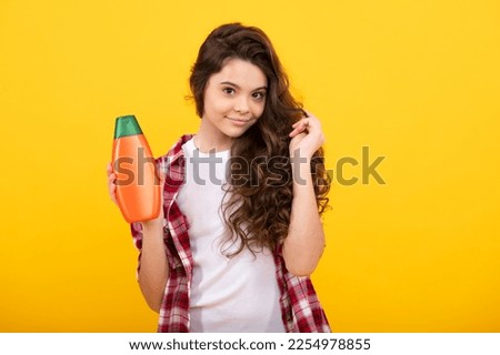 Teenager child girl showing bottle shampoo conditioners or shower gel. Hair cosmetic product. Bottle for advertising mock up copy space. Happy teenager, positive and smiling emotions of teen girl.