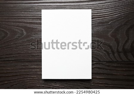 Blank card mockup on wooden background, top view, flat lay. White empty holiday card mock up on brown table