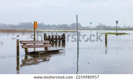 Olst Wijhe, The Netherlands - January 21, 2023: Wooden bench and fence in flooded area near ferry pond Olsterveer at crossing IJssel river in Olst Wijhe Welsum in Overijssel in The Netherlands Royalty-Free Stock Photo #2254980957