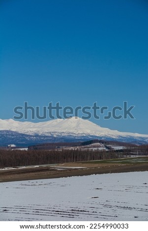 Upland field where snow remains and snowy mountains
