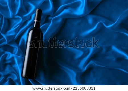 Bottle of red wine on a blue satin background. Top view.