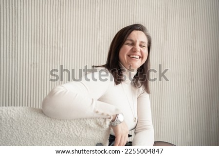Laughing business woman closed her eyes in beige office clothes. Good mood in the office during the day.