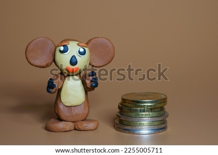 A toy cheburashka with coins on a brown background. A child's toy.