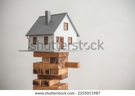 Modern house on wood tower block game white wall background copy space. Mortgage loan for buying home or real estate property, money risk management in financial, foreclosure and bankruptcy  concept.