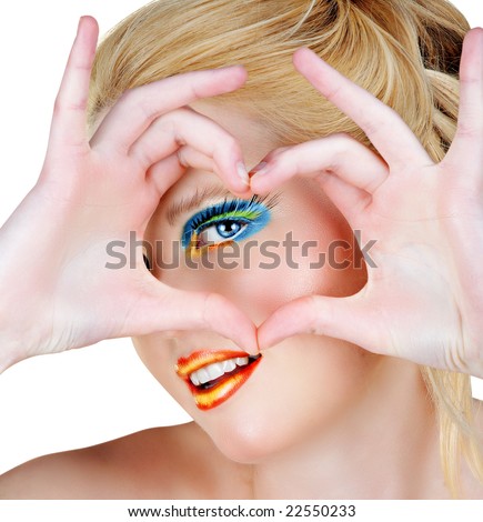 Blond woman with bright make-up and long false lashes showing heart symbol with her hands, smiling