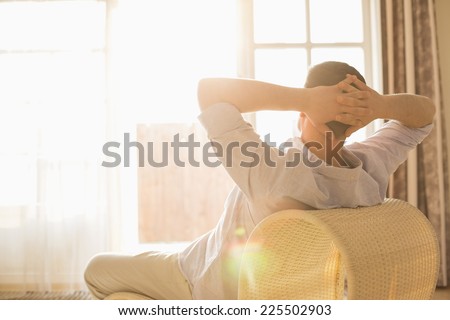 Rear view of man relaxing on chair at home Royalty-Free Stock Photo #225502903
