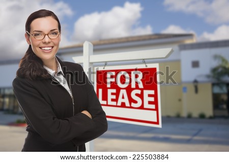 Attractive Serious Mixed Race Woman In Front of Vacant Retail Building and For Lease Real Estate Sign.