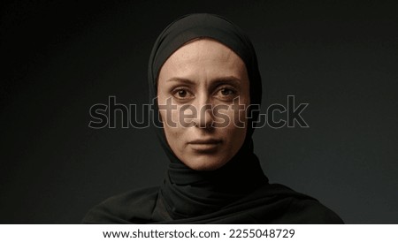 Portrait of beautiful young Arab muslim woman in black traditional hijab looking straight to camera and smiling. Close up of female pretty face with smile. Arabian headscarf Royalty-Free Stock Photo #2255048729