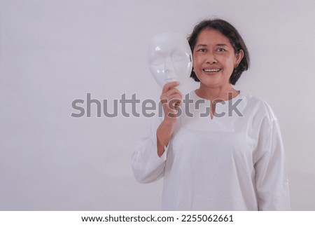 A woman taking off her mask, smiling.  Royalty-Free Stock Photo #2255062661