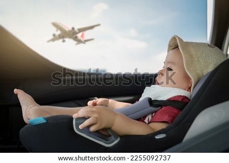 Baby boy Travel sitting in the car seat, looking outside the window. see the airplane in the sky. family travel concept. Transportation Concept. Royalty-Free Stock Photo #2255092737