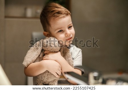 Portrait of a little boy hugging a bunny in a bathroom.