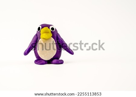 Hand made purple Play dough plasticine penguin with yellow bill isolated on a white background  with copy space