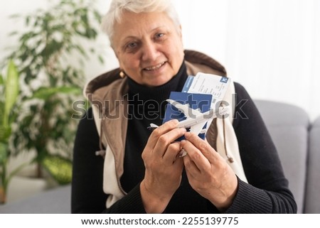 old woman holding Passport, boarding pass and toy airplane