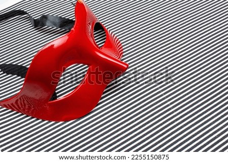 red carnival mask on a black and white striped background