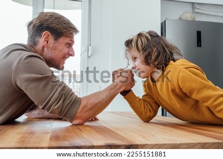 Father competing in arm wrestling with teen son, family spending time together