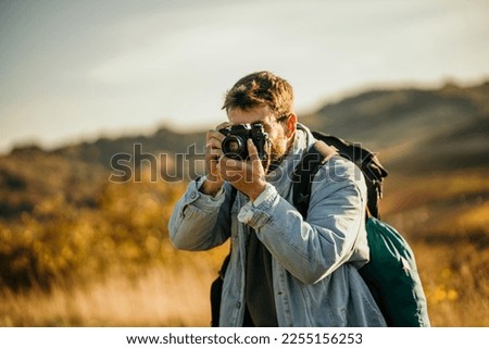 Young photographer hiking on mountains and photographing nature.