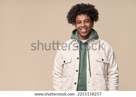 Young happy hipster African American teen guy isolated on pastel beige background. Smiling cool curly ethnic generation z teenager student model standing looking at camera posing for portrait. Royalty-Free Stock Photo #2255158257