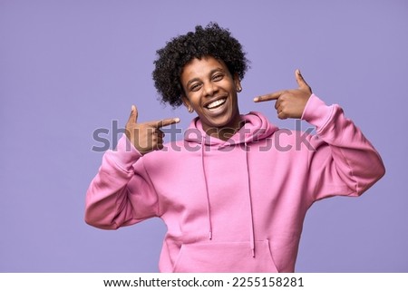 Happy African American teen guy pointing at dental white teeth advertising whitening. Smiling student showing healthy teeth perfect natural orthodontic smile standing isolated on purple background. Royalty-Free Stock Photo #2255158281