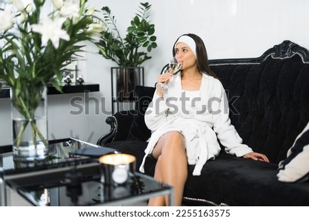 Young girl relaxing with a glass of wine in spa hotel dressed in white towel. High quality photo