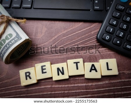 Keyboard and toys word with the word RENTAL on wooden background.
