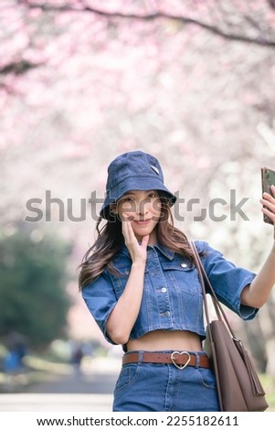 Woman take selfie with cherry blossoms or sakura flower blooming in the park