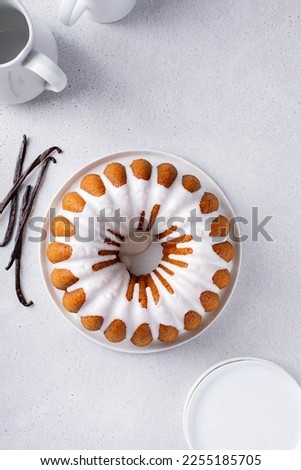 Vanilla bundt cake drizzled with powder sugar glaze with vanilla beans overhead view with copy space