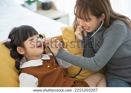 Asian mother and her daughter child girl playing in bedroom. Role-play doctor and patient.