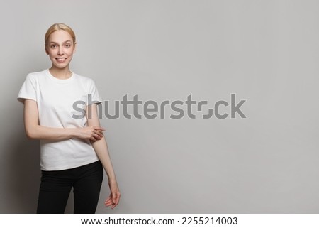 Portrait of young happy woman looking in camera standing against white studio wall background with copy space