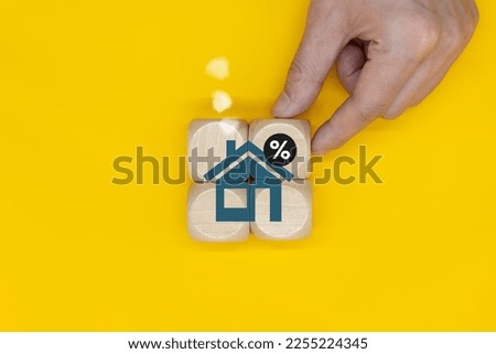 Interest rate financing and mortgage rate concepts. Put a cube block with a tree house and a percent icon in your hand.