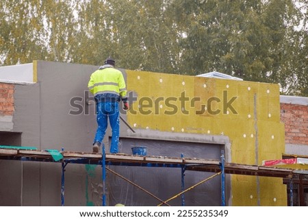 view of construction worker in doing insulation of wall at construction site